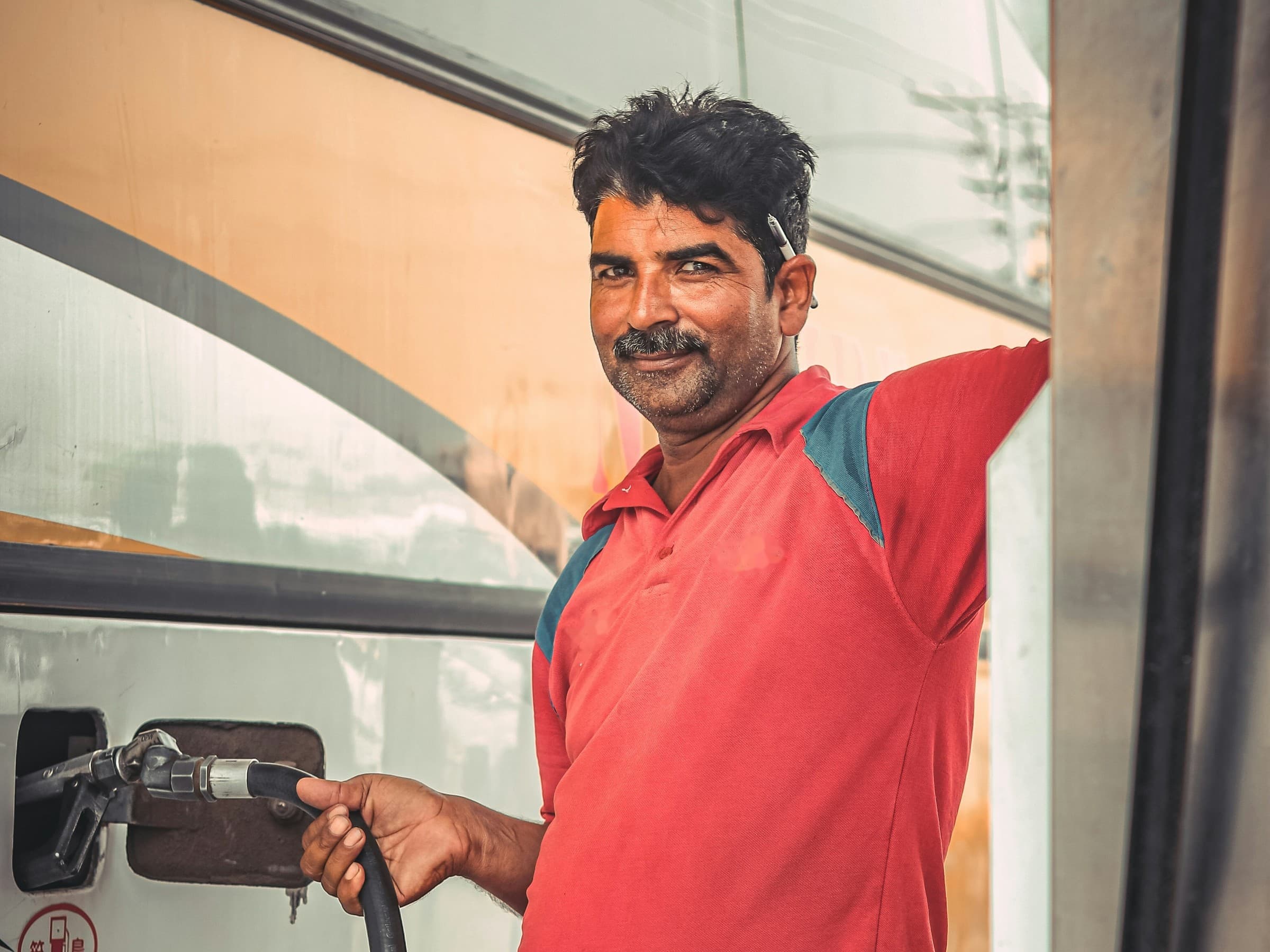 A forecourt attendant refuelling a bus